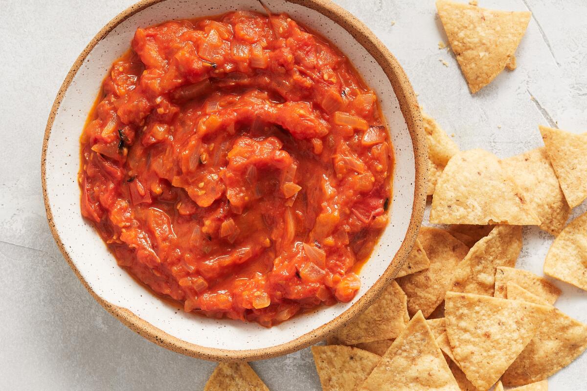 A bowl of tomato-habanero salsa, with tortilla chips.