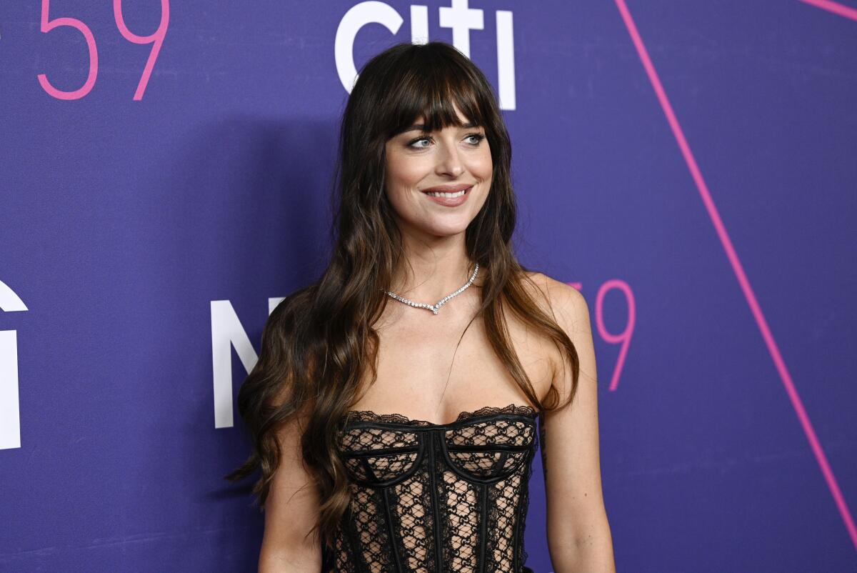 Actor Dakota Johnson smiles toward unseen cameras.