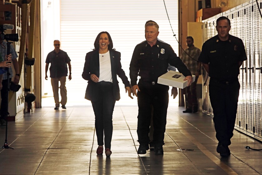 Vice President Kamala Harris walks with two men in uniform