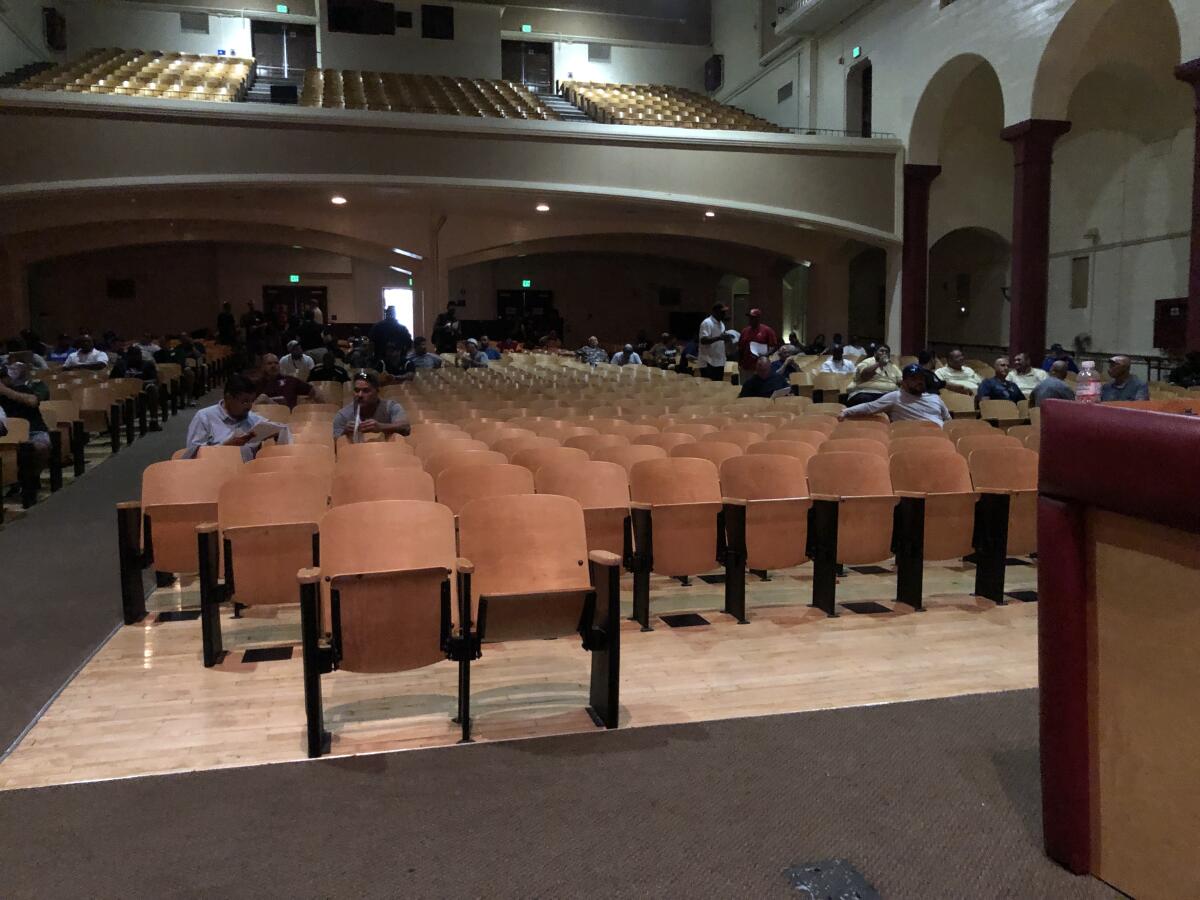 City Section football coaches sit in the Fairfax High auditorium, with many empty seats, for a meeting.