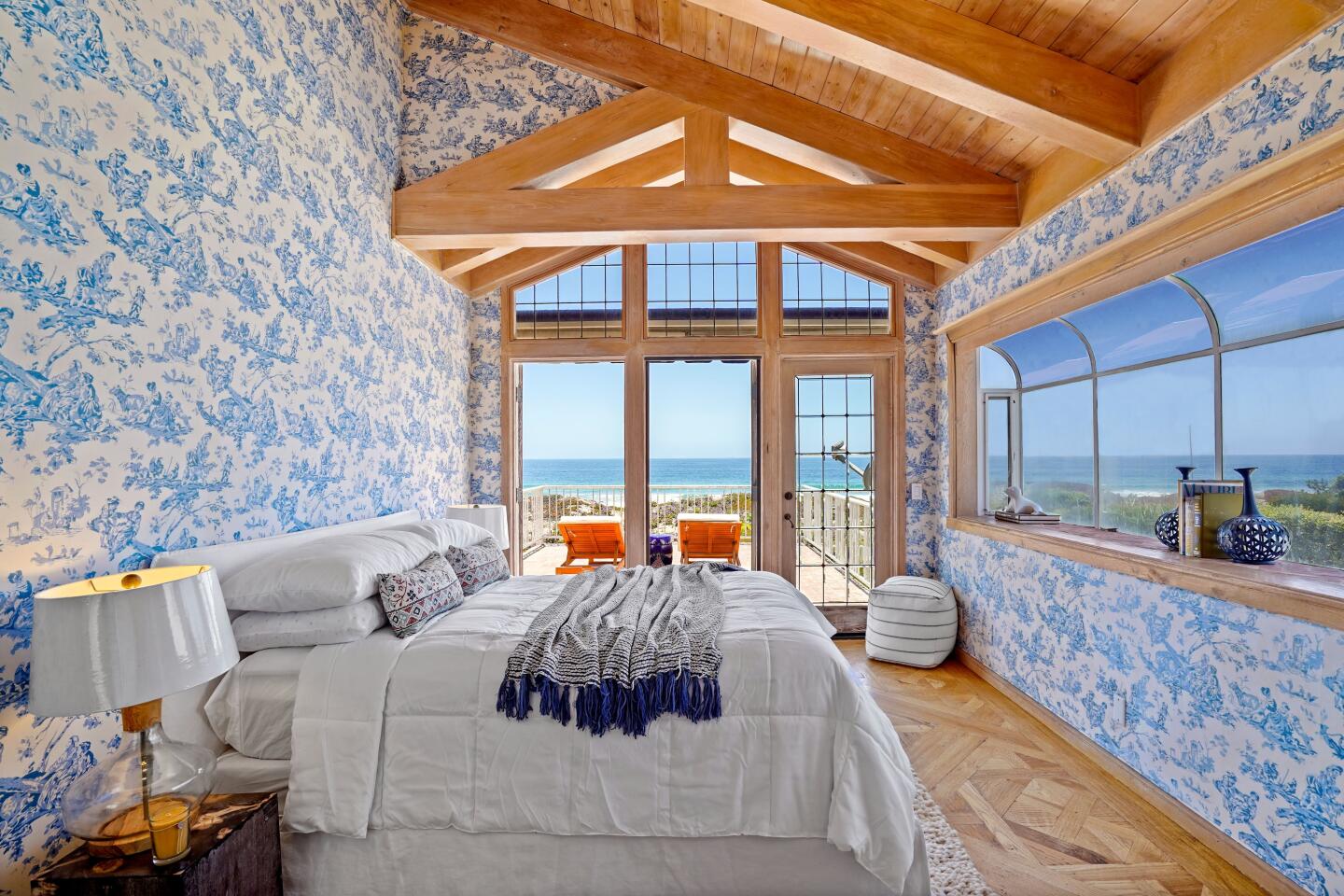 A bedroom has a bank of windows, a glass door, slopedceiling and blue and white walls.