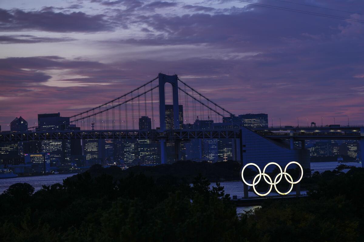The Olympic rings are lighted in front of the city of Tokyo.