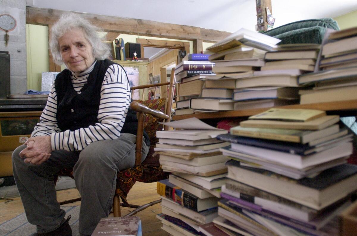 Grace Paley sits beside a pile of books in her home