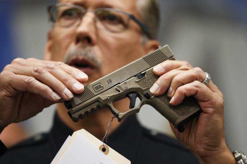 Los Angeles Police Det. Ben Meda holds a handgun during a news conference at the Hollywood Community Police Station Thursday, July 5, 2018, in Los Angeles. More than 40 firearms were seized in a recent joint task force operation, authorities said Thursday. (AP Photo/Jae C. Hong)