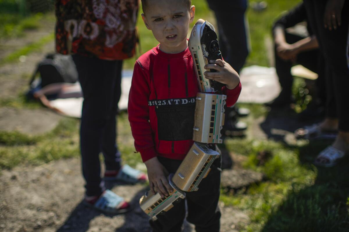 Un niño sostiene un tren de juguete en el exterior de su casa, que sufrió graves daños tras un ataque ruso 