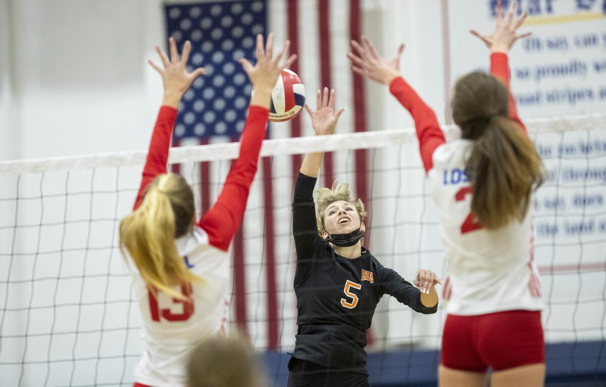 Huntington Beach's Lillian Perkins hits against Los Alamitos' Olivia Panzica, left, and Amanda Zidonis.