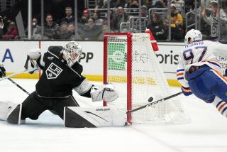 Los Angeles Kings goaltender Cam Talbot, left, reaches to stop a shot by Edmonton Oilers center Connor McDavid.