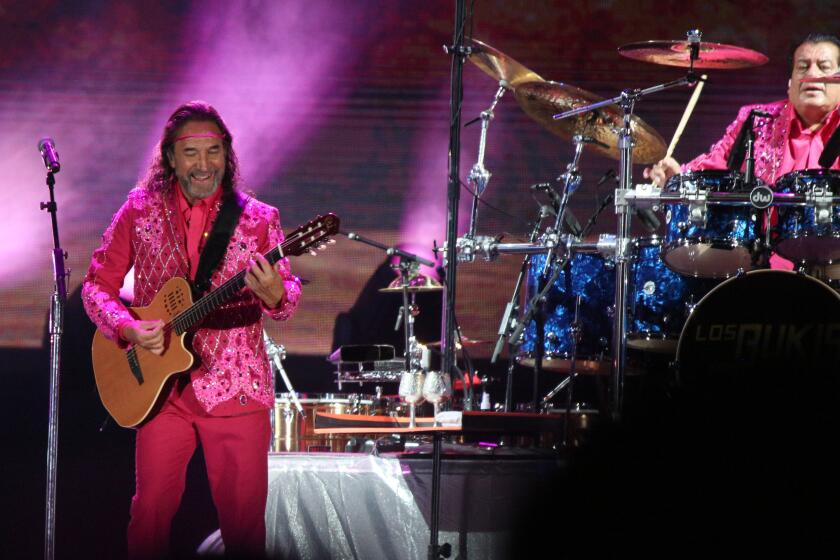 Los Bukis frontman and co-founder Marco Antonio Solis, left, and drummer Pedro Sanchez, right, play with the legendary Mexican grupera band for their Una Historia Cantada Tour at the Los Angeles Coliseum on Thursday, Aug. 18, 2022.