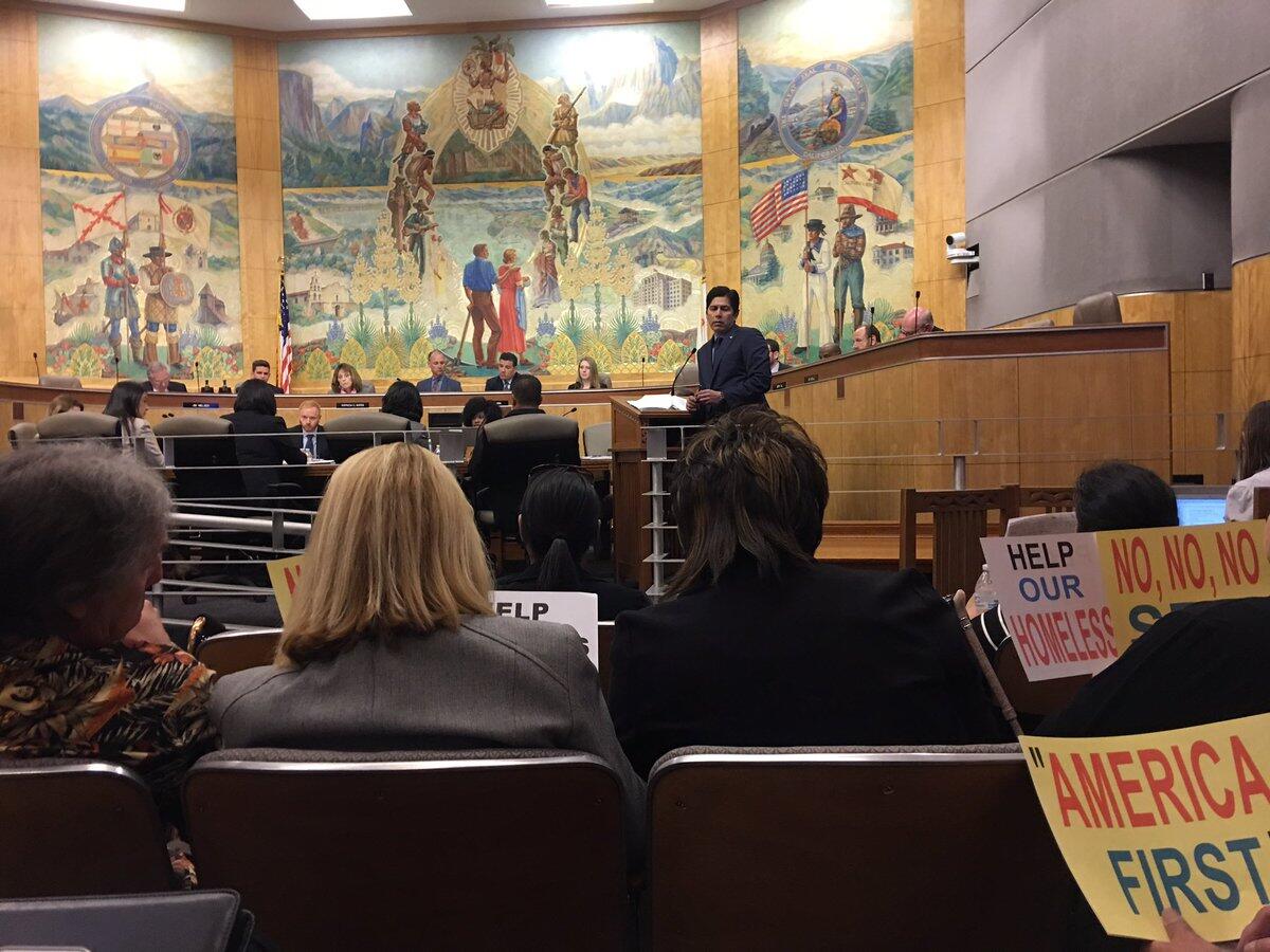 Audience members hold signs at a hearing on immigration bills before the state Senate Appropriations Committee.