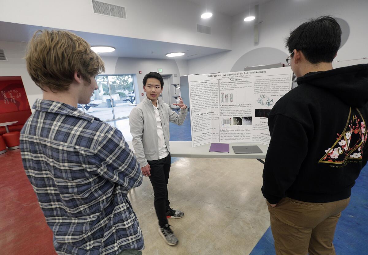 Jingyu Yan, 15, talks about his science project "3D Structural Investigation of an Anti-viral Antibody" to interested students during the science fair at La Cañada High.