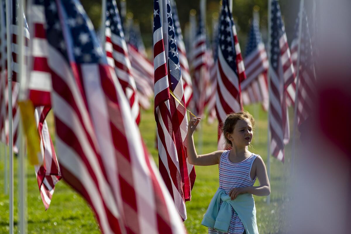 Mary Bailey, 8, pauses at one of hundreds of American flags flying over the Palmdale Healing and Honor Field.