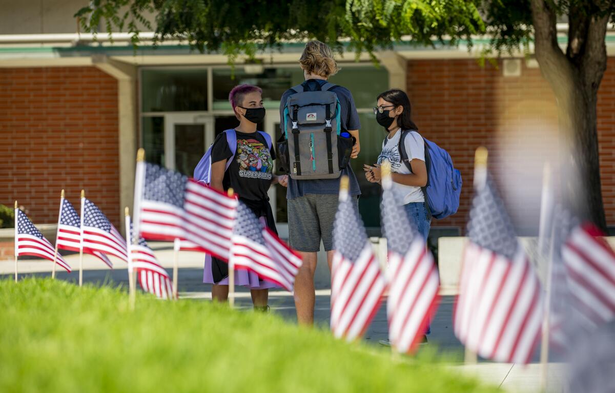 Students visit with each other near 500 American flags at Edison High School on Friday. 