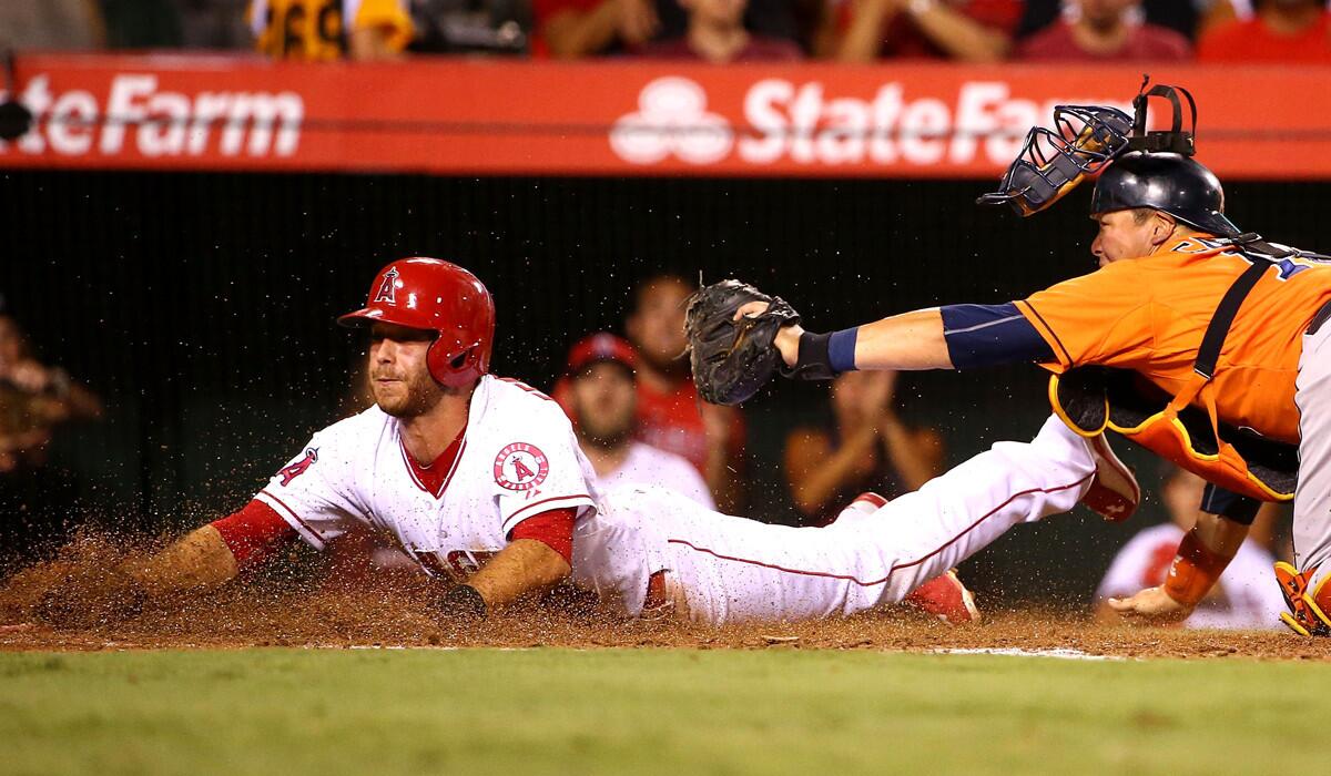 Angels second baseman Taylor Featherston slides safely into home plate as Houston Astros catcher Hank Conger holds up a late tag in the second inning on Friday.