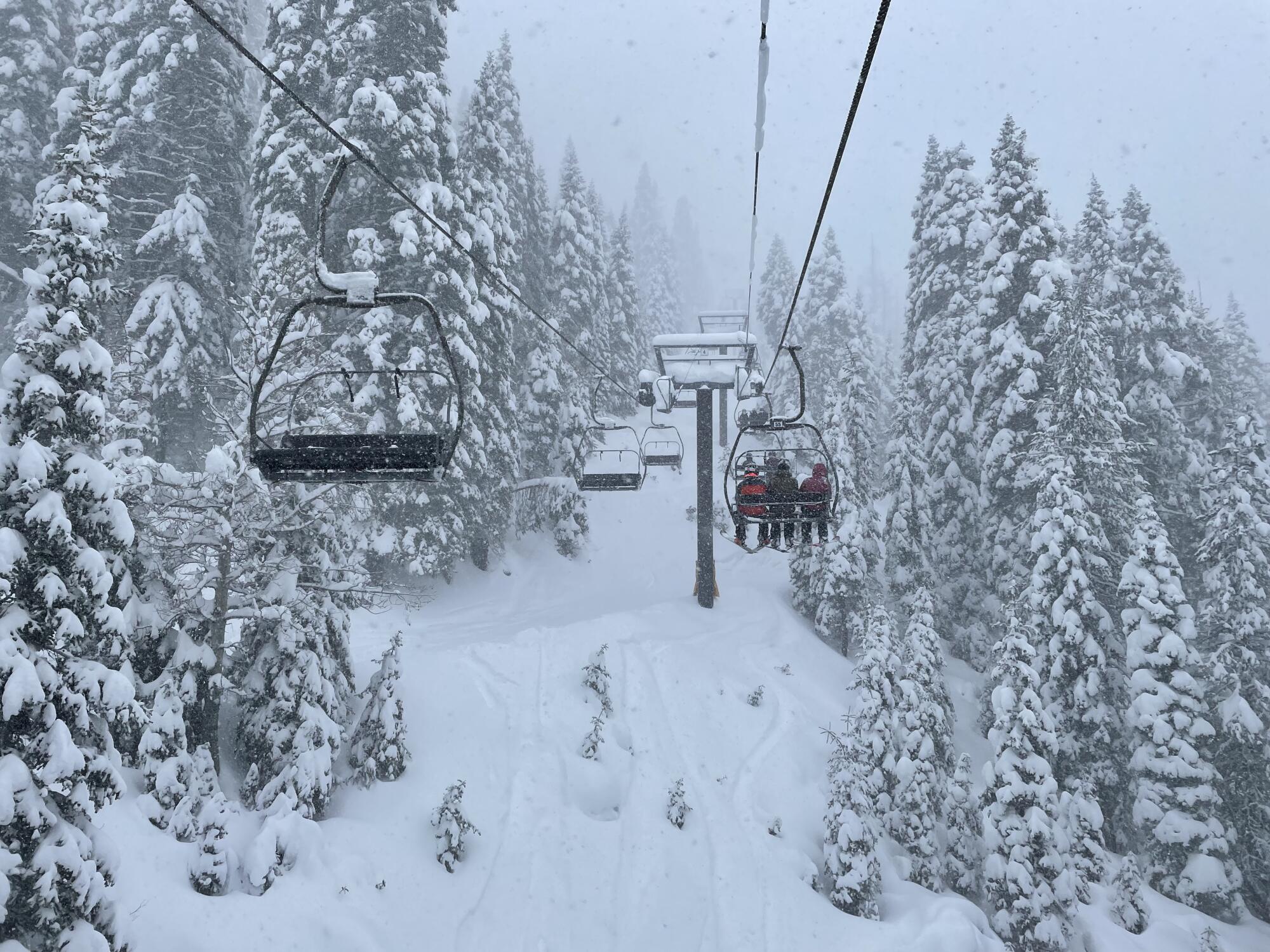 Three people ride on a ski lift