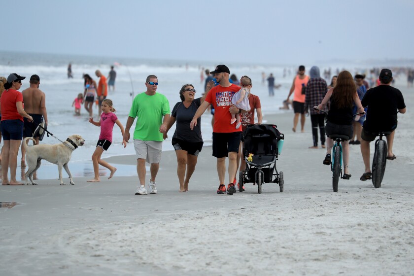 People walk down the beach last April in Jacksonville Beach, Fla.