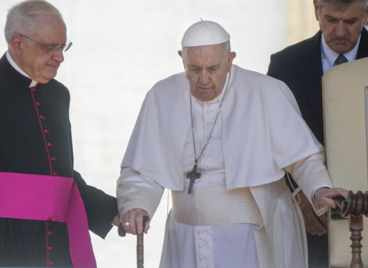 Pope Francis being steadied by an aide