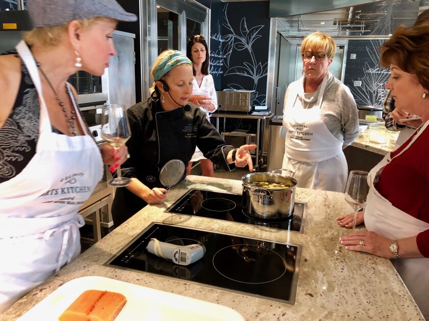 Noëlle Barille (with headset) coaches students in a French cooking class aboard Regent Seven Seas Explorer, which offers cruisers a variety of classes.