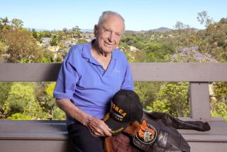 Escondido, CA - June 13: On a warm afternoon 97 year old war veteran Royce Williams holds one of his many caps and his flight jacket as he sits on his rear patio deck overlooking a canyon in the Mountain Meadows area of Escondido. (Charlie Neuman / For The San Diego Union-Tribune)