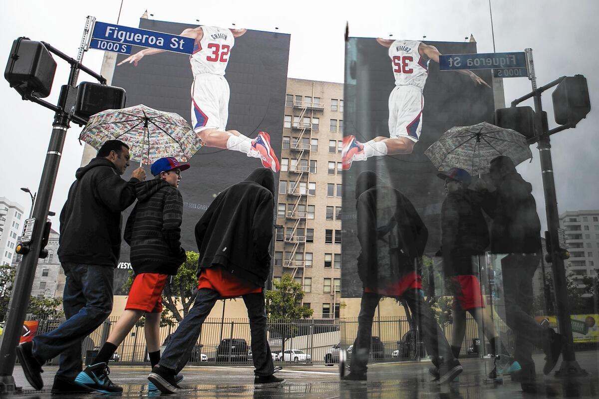 A mural featuring a headless Blake Griffin towers over the rain-slickened intersection of Figueroa Street and Olympic Boulevard in downtown Los Angeles.
