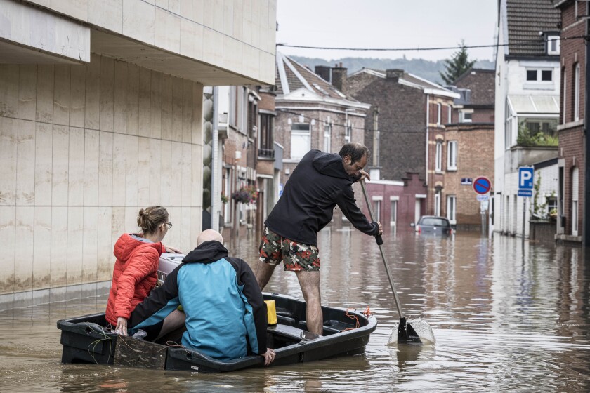 A man rows a boat down a residential street after flooding in Angleur, Province of Liege, Belgium.