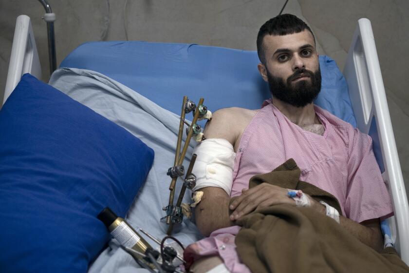 Mujahid Abadi, 24, poses for a portrait at the Ibn Sina Specialized Hospital where he is recovering from gunshot wounds and burns in the West Bank city of Jenin, Tuesday, June 25, 2024. When the Palestinian man stepped outside to see if Israeli forces had entered his uncle's neighborhood, he was shot in the arm and the foot. That was only the start of his ordeal. Hours later, beaten and bloodied, he found himself strapped to the searing hood of an Israeli military jeep driving down a road. (AP Photo/Maya Alleruzzo)