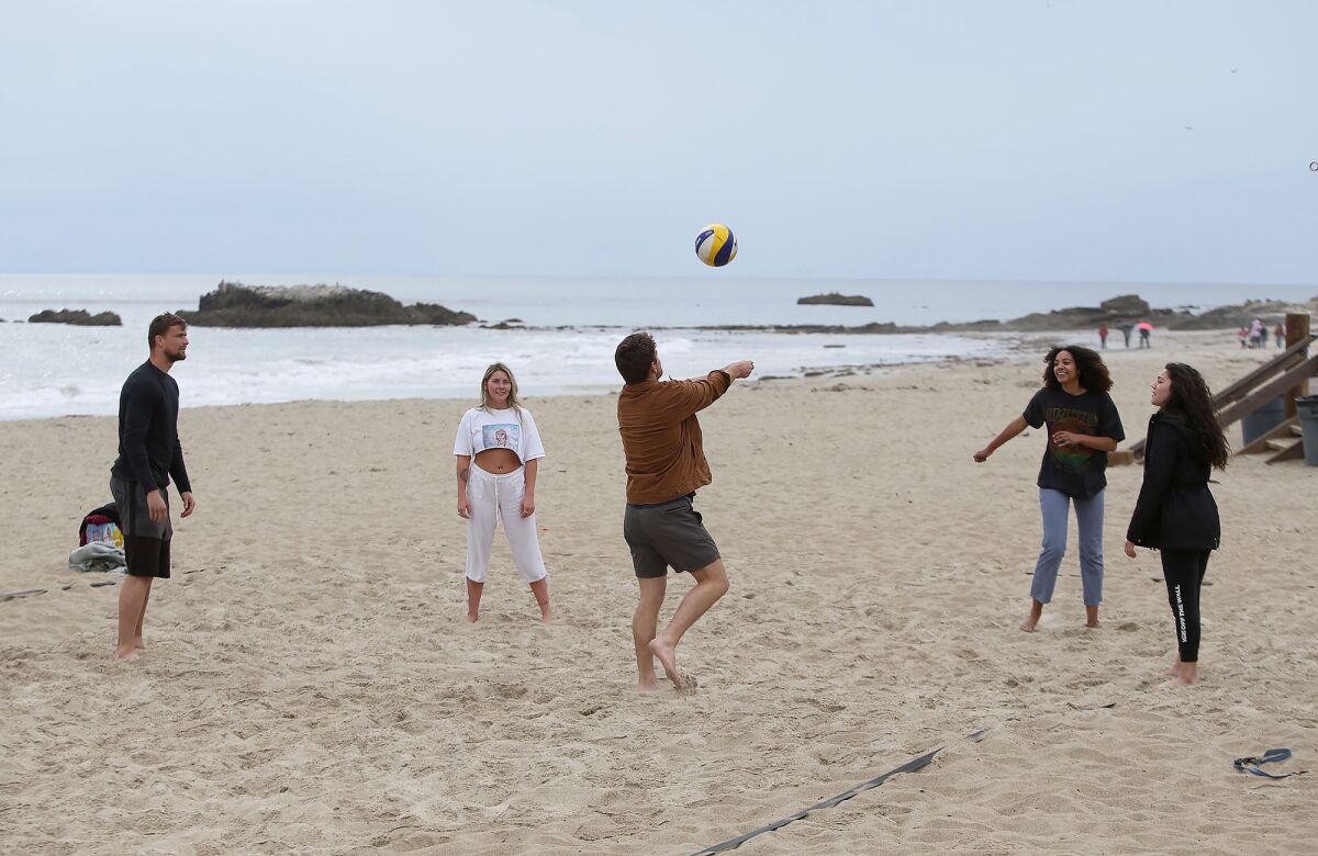 A group of friends plays volleyball without a net on Main Beach on Monday morning as Laguna Beach prepared to close city beaches and adjacent parks, including Main Beach, in an effort to prevent crowding that could help spread the coronavirus.