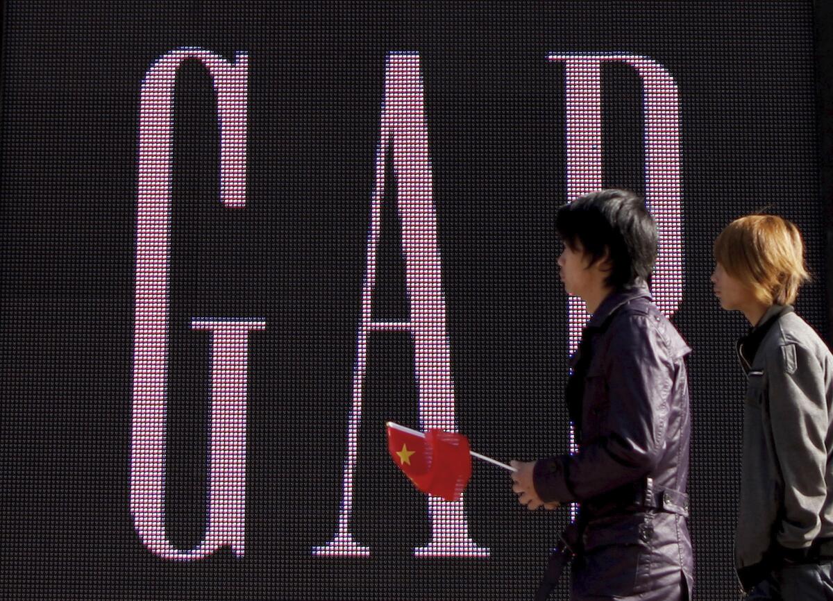 A man carries a Chinese flag as he walks past U.S. retailer GAP's newly-opened flagship store in Beijing.
