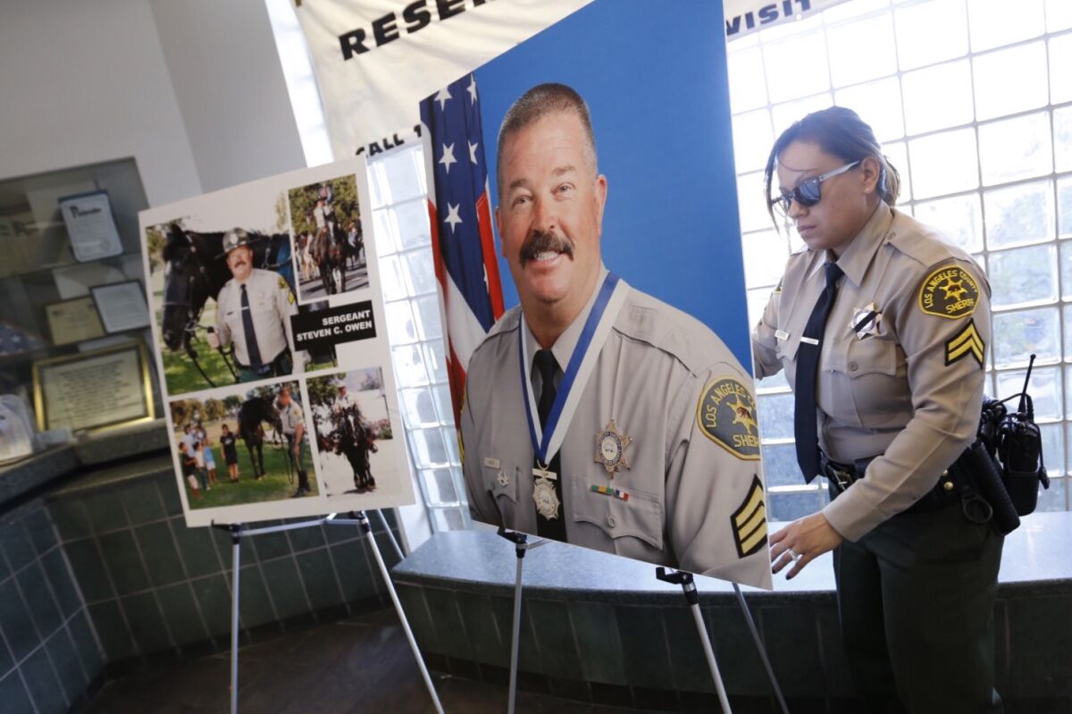 A sheriff's deputy places poster-sized portraits of the late Sgt. Steve Owen on easels
