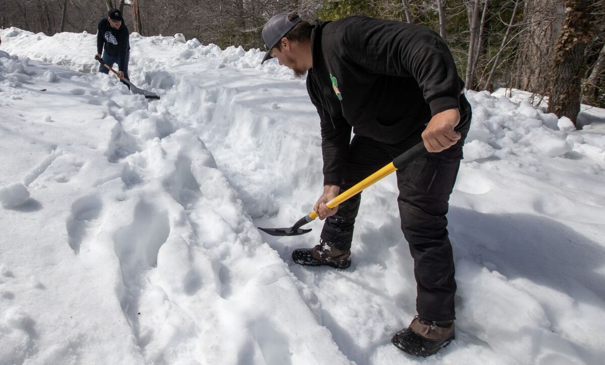 two people shovel a path covered in snow