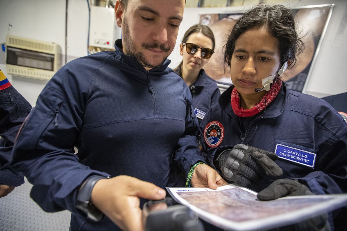 Mars Desert Research Station crew members Vittorio Netti, left, and Marlen Castillo, right, look over a map and GPS coordinates. (Brian van der Brug / Los Angeles Times)