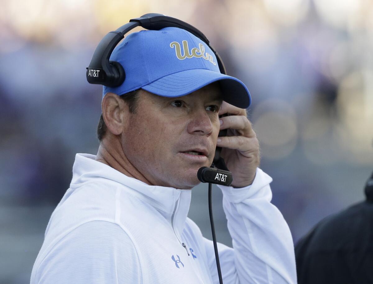 UCLA coach Jim Mora adjusts his headset and looks toward the field during a game against Washington.