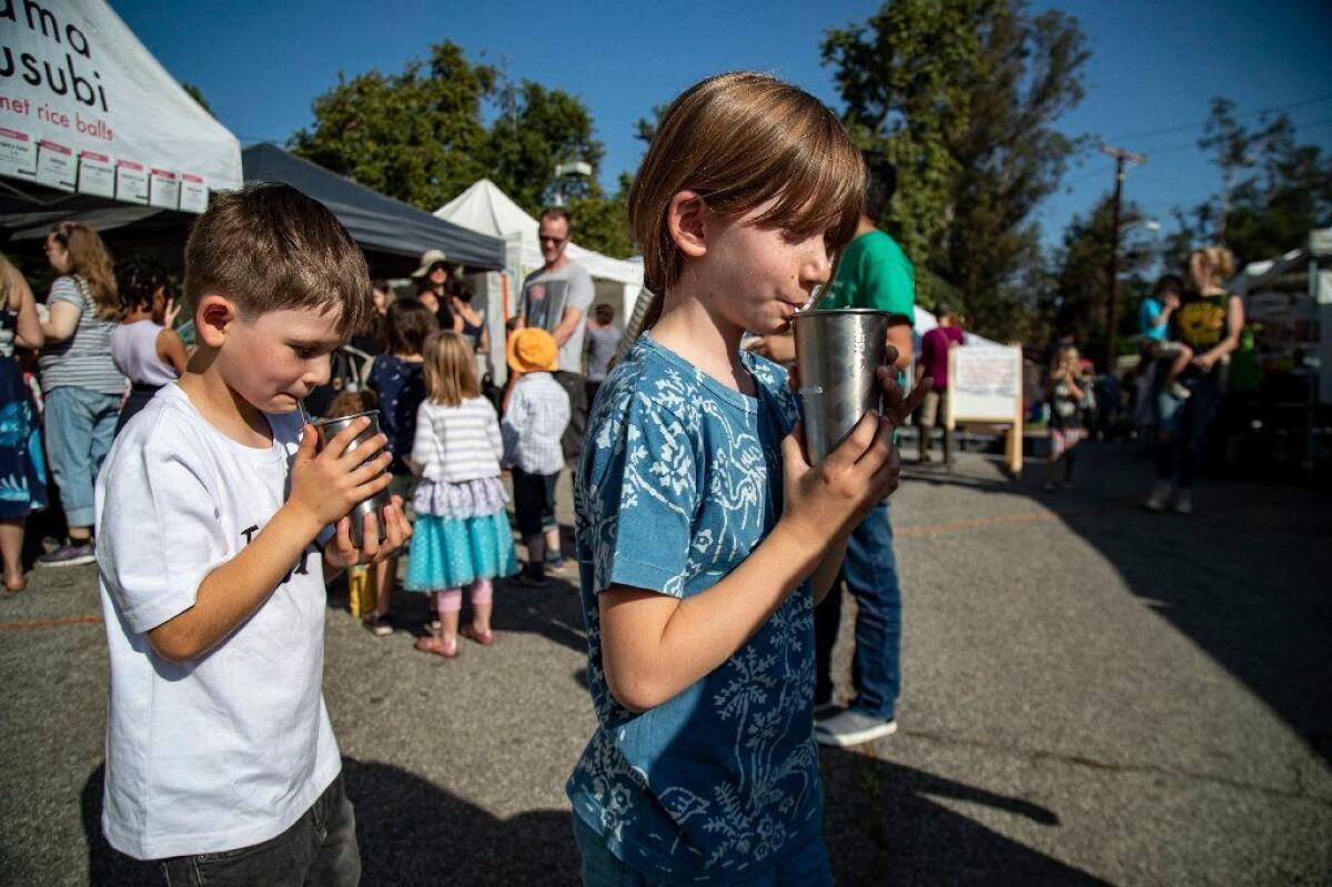 James and Isla drink lemonade in reusable cups that they brought with them to the farmers market.