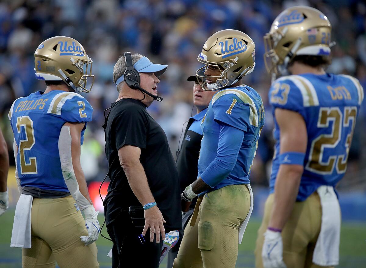 UCLA coach Chip Kelly talks with quarterback Dorian Thompson-Robinson on the sideline during the 2021 season.