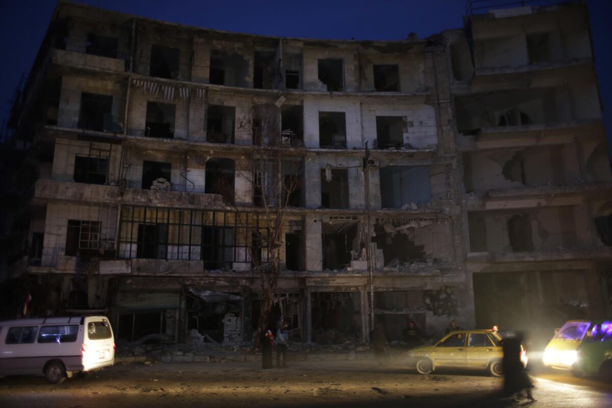 Gente esperando junto a un edificio destruido en el barrio de Shaar, antes dominado por los rebeldes, en Aleppo, Siria, el martes 17 de enero de 2017. (AP Foto/Hassan Ammar)