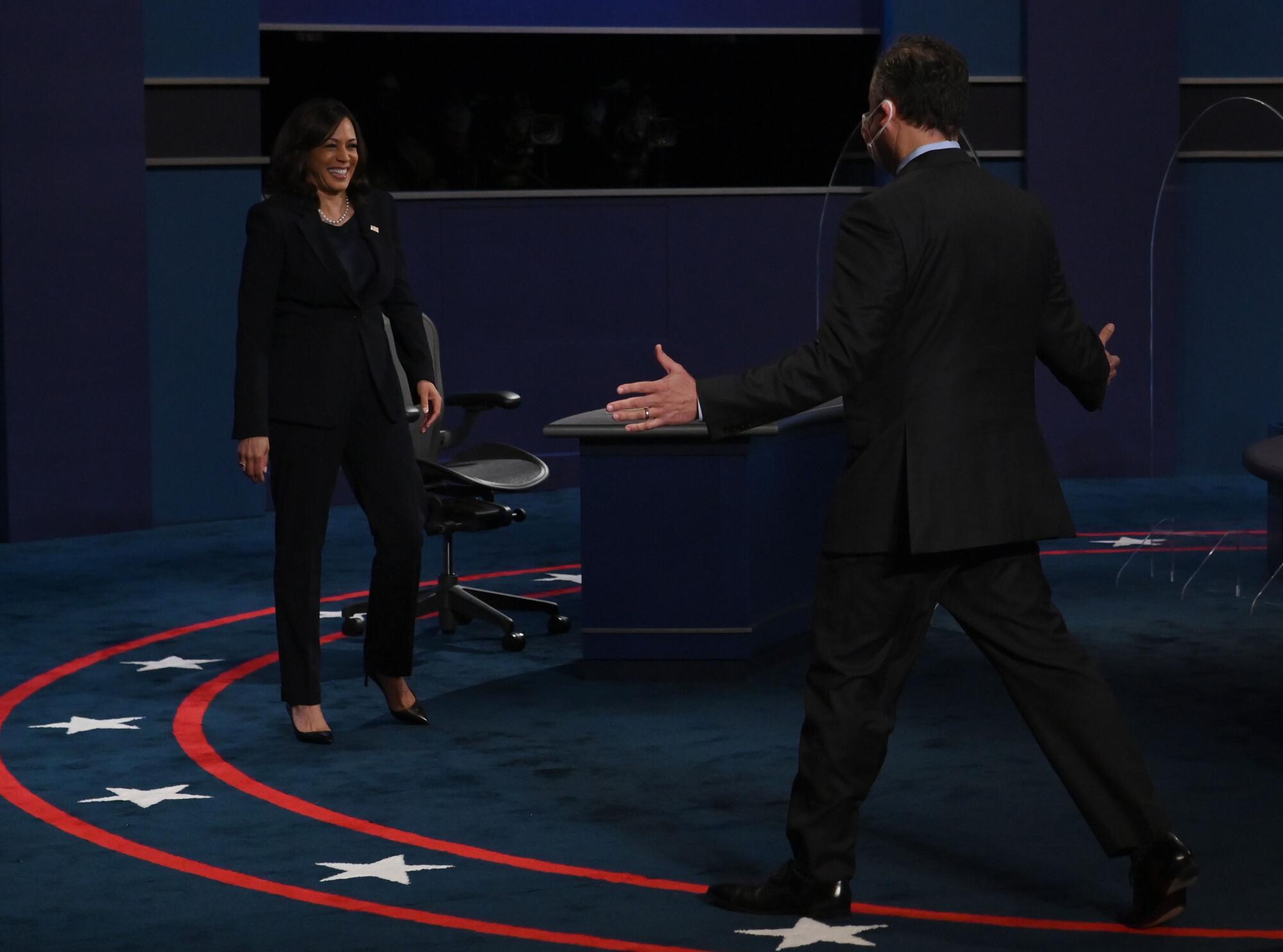 Kamala Harris smiles as her husband stretches his arms out for a hug on the debate stage