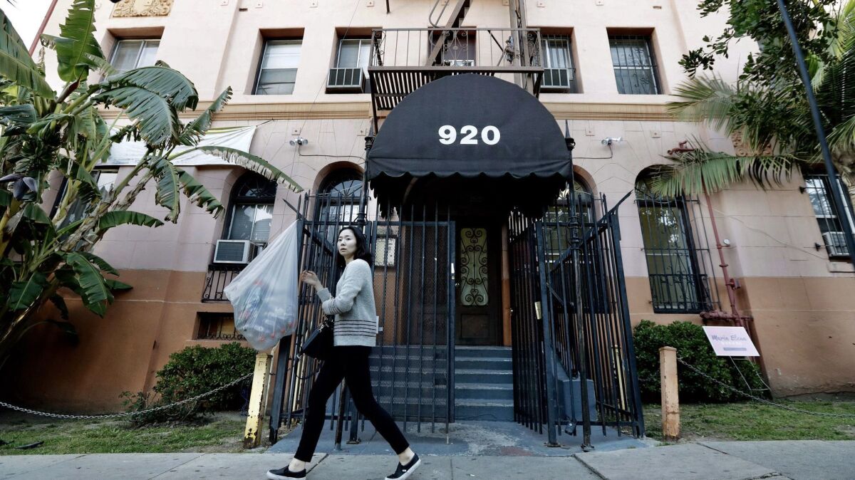 A woman walks past an apartment building in Koreatown where one person was found dead.