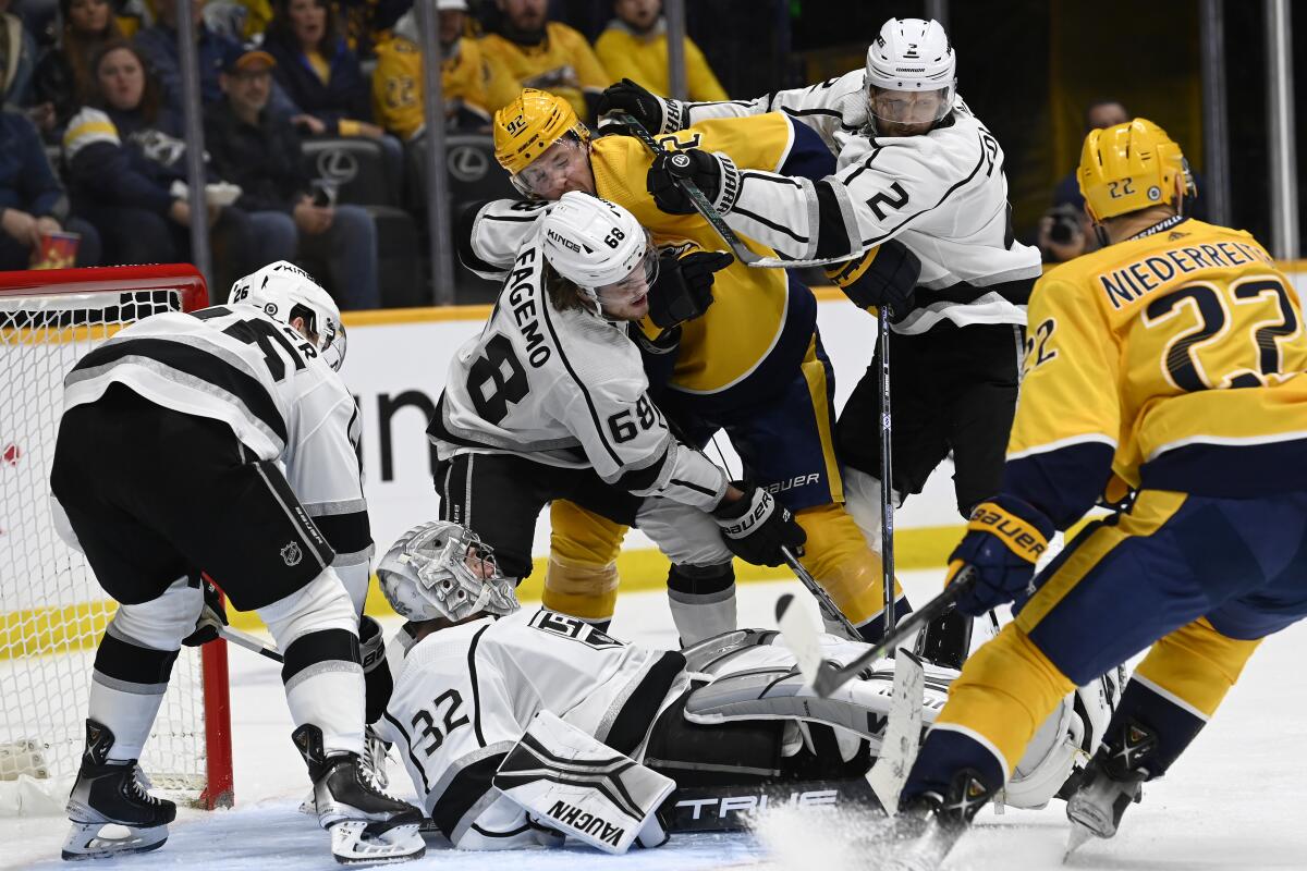 Kings goaltender Jonathan Quick (32) tries to keep the puck underneath him as players battle for position in front of him.