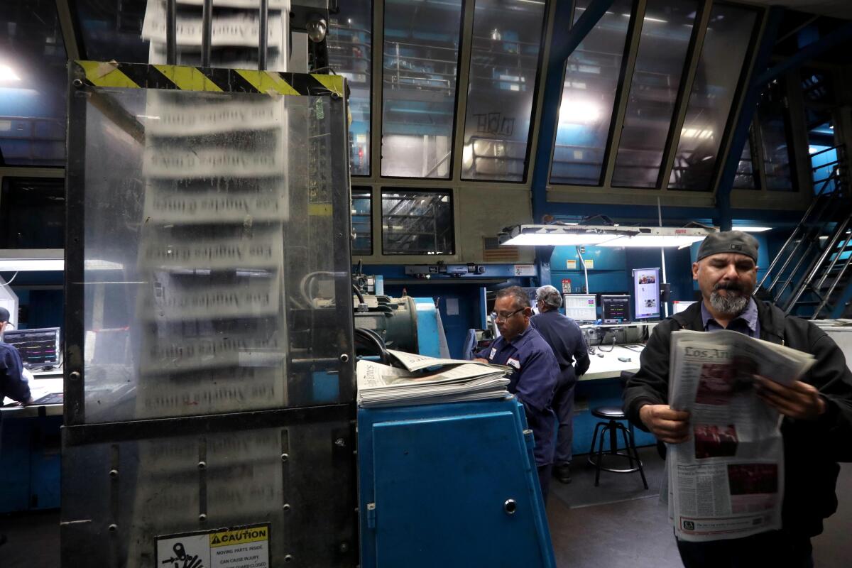 A worker holds a newspaper inside a printing plant.
