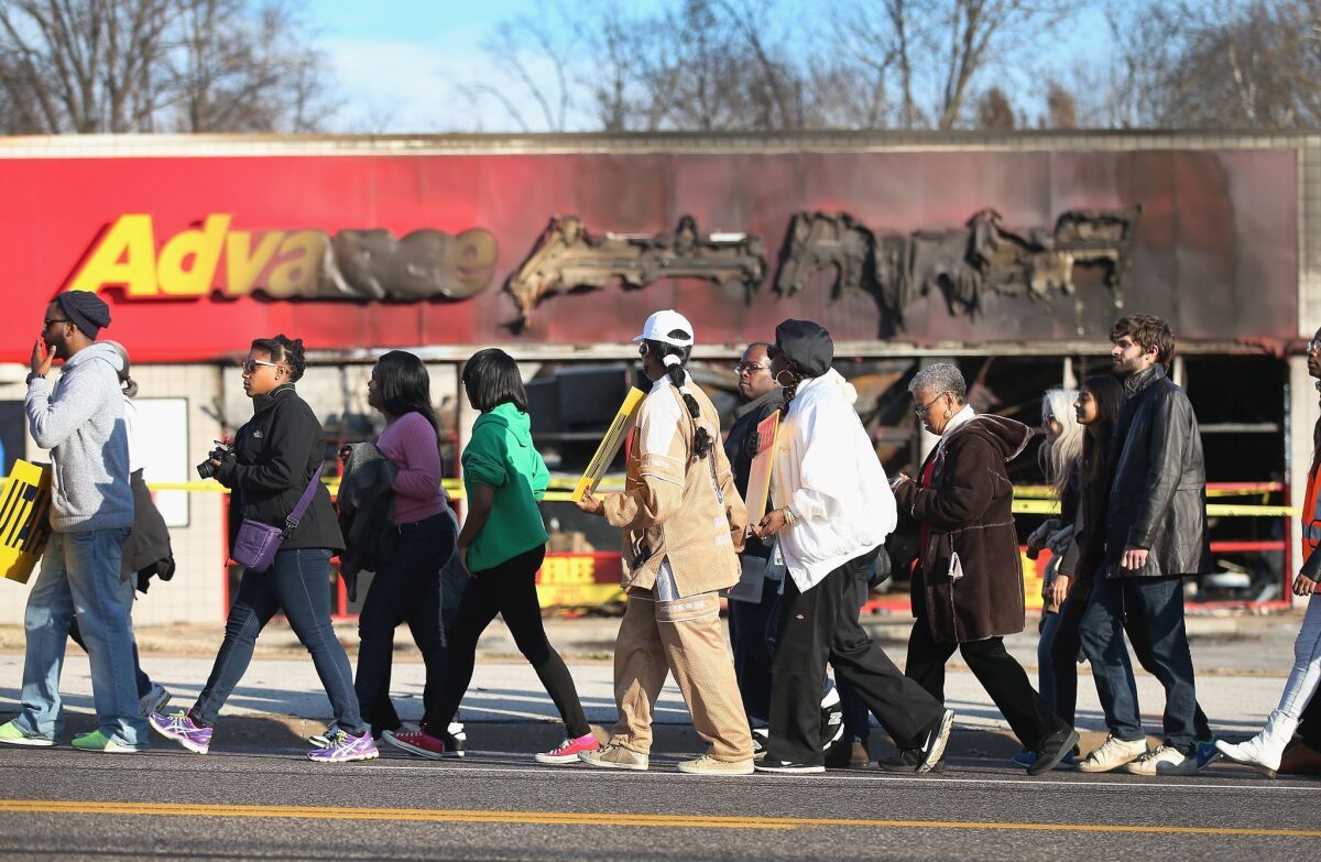 NAACP members and supporters pass by an auto parts store in Ferguson, Mo., that was destroyed by rioters as they walk Saturday on the first day of a planned seven-day, 120-mile march to the governor's mansion in Jefferson City, Missouri's capital.