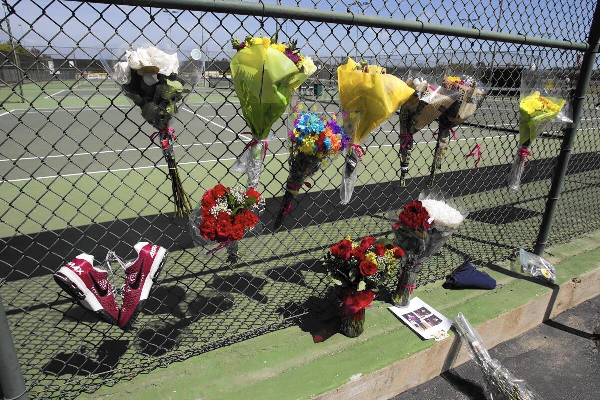 Flowers are put on the fence of the Costa Mesa High School tennis courts in honor of coach Brian Ricker before a match on Tuesday afternoon.