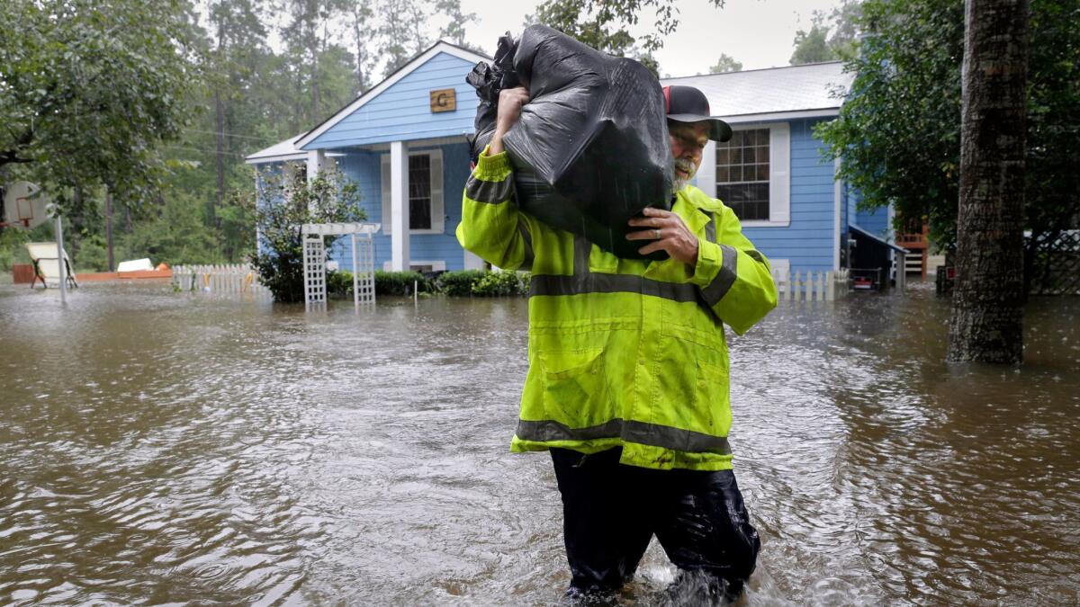 Mike Battles, brother in law of homeowner Doug Glassel, wades through flood waters as he carries food from Glassel's flooded two-story home in Spring, Texas on Aug. 29.