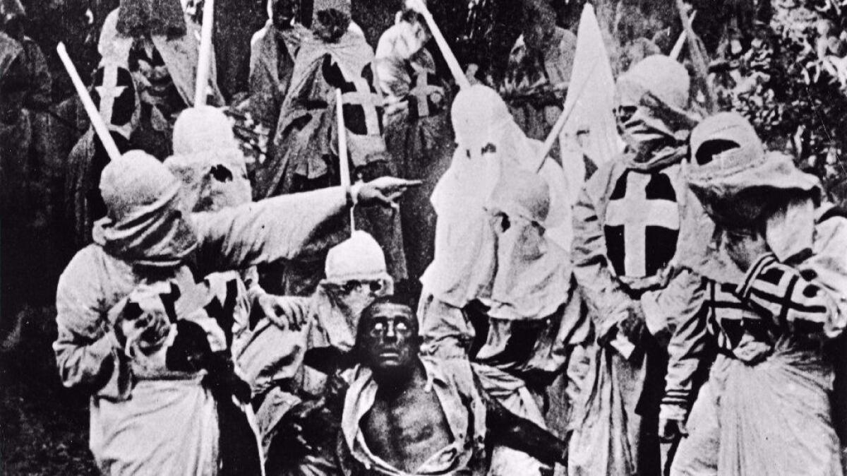 Actors costumed in the full regalia of the Ku Klux Klan chase down a white actor in blackface in a still from "The Birth of a Nation."