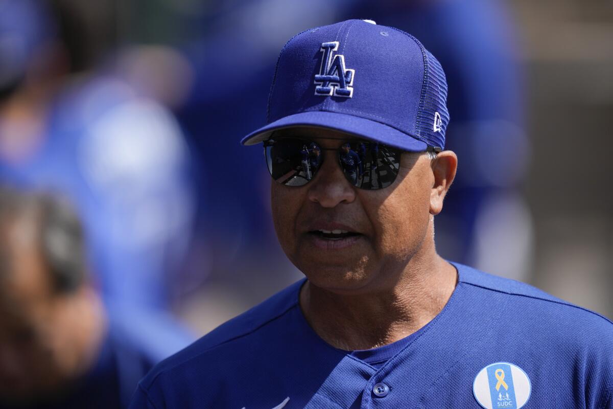 Dodgers manager Dave Roberts stands in the dugout before a spring game against the Chicago White Sox.