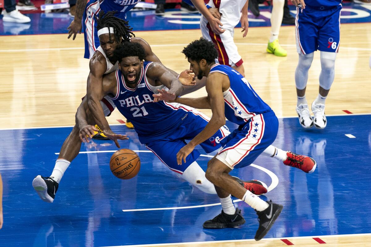 Philadelphia 76ers' Joel Embiid battles with Miami Heat's Precious Achiuwa for a loose ball.