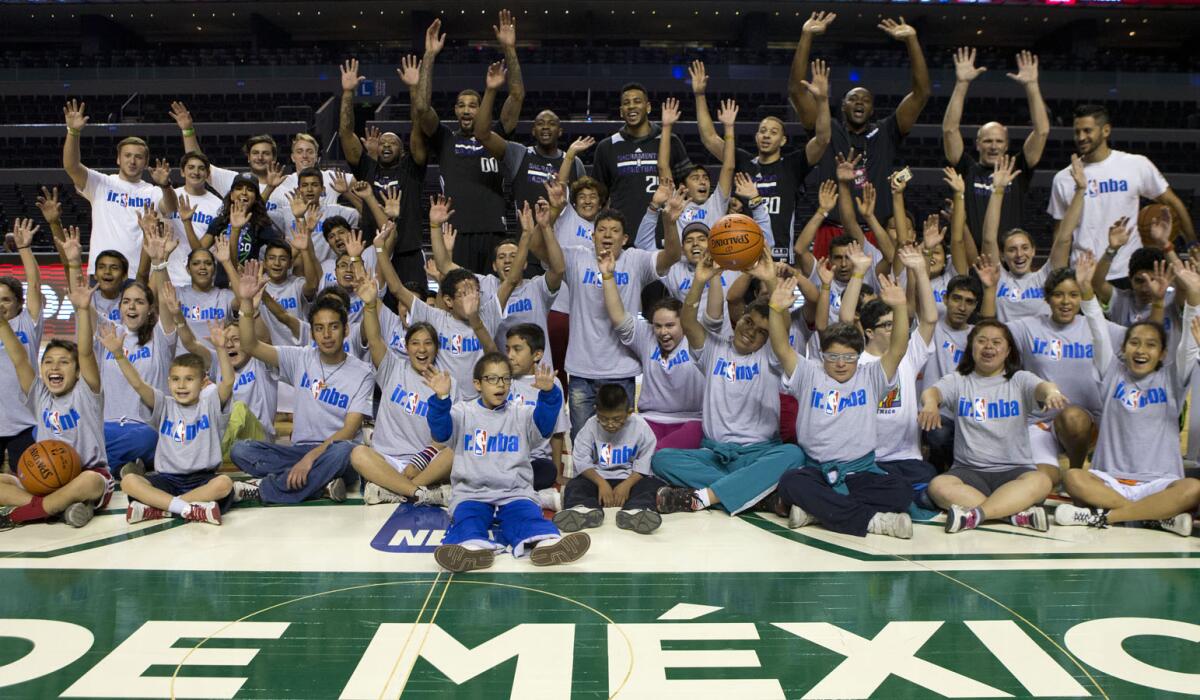 Jugadores de los Sacramento Kings posan con niños en una convivencia realizada en la Arena Ciudad de México, en diciembre de 2015.