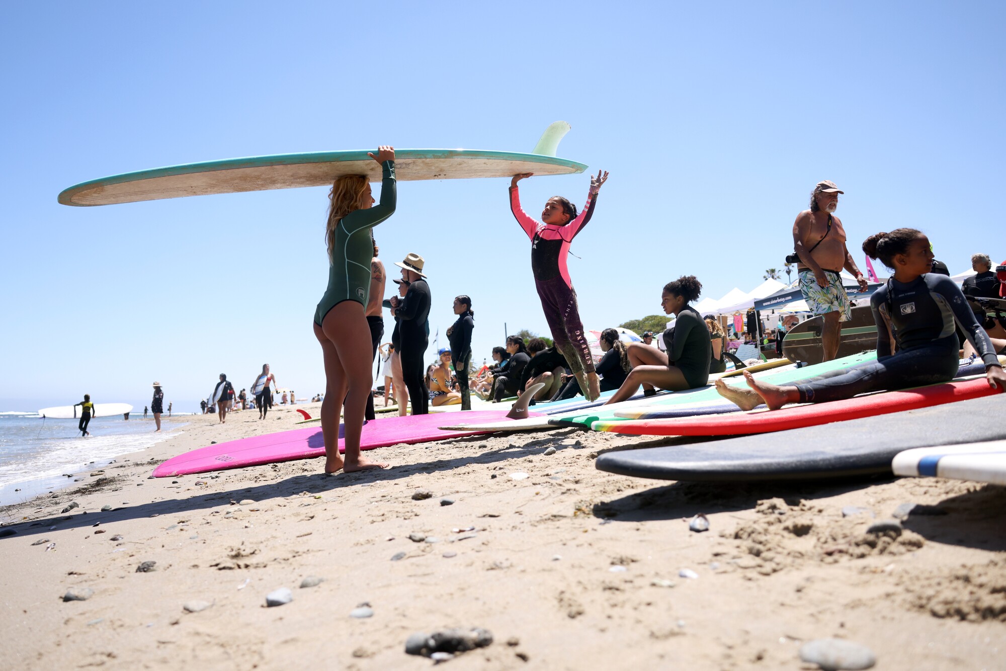 Dahlia Castaneda saute pour toucher une planche juste avant d'entrer dans l'eau pour une leçon de surf à First Point à Malibu.