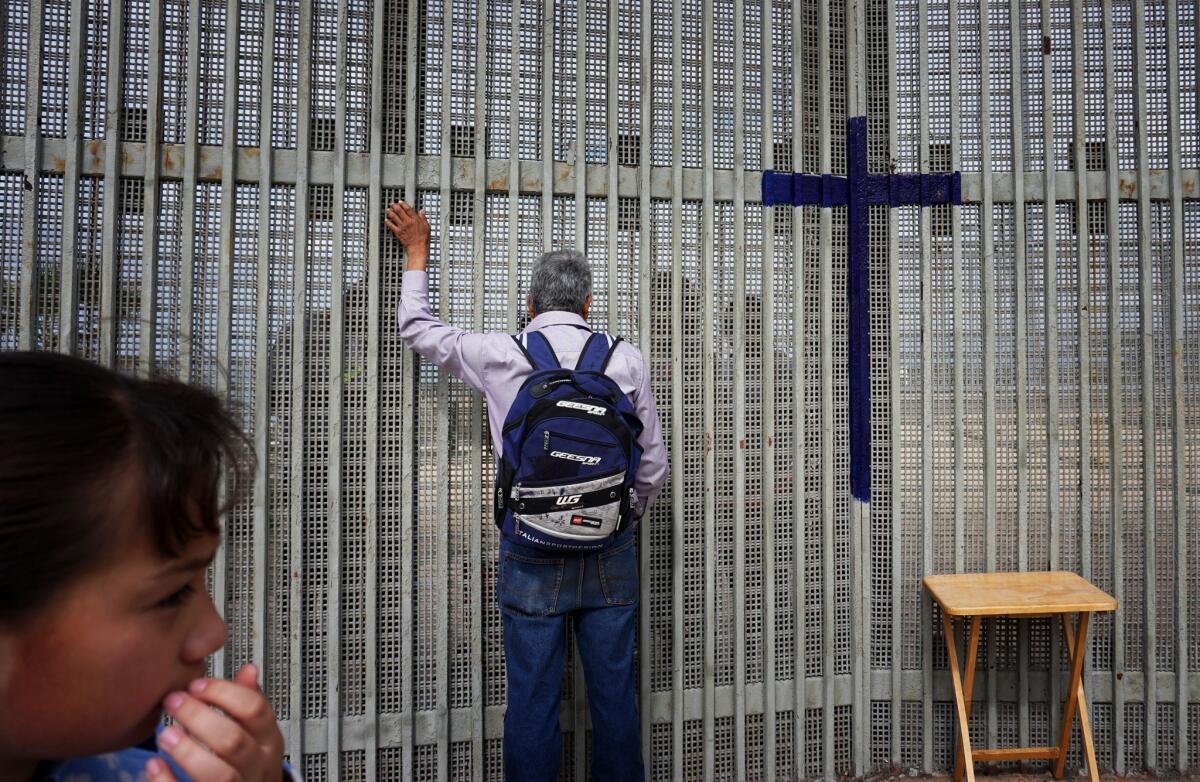 A man visits with relatives along the U.S.-Mexico border wall.