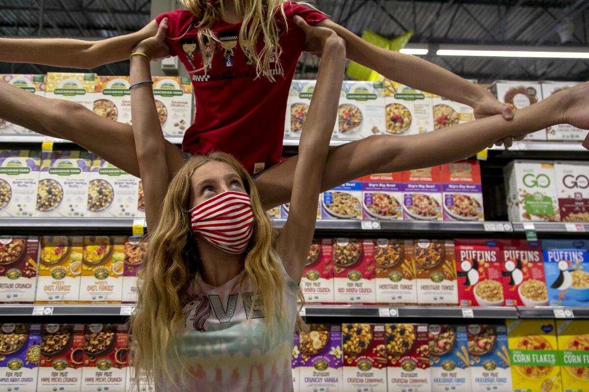 At Whole Foods, Playa Vista, Brinkley Baker, 15, lifts her sister Bixby Baker, 11, above her head on Sept. 11, 2020.