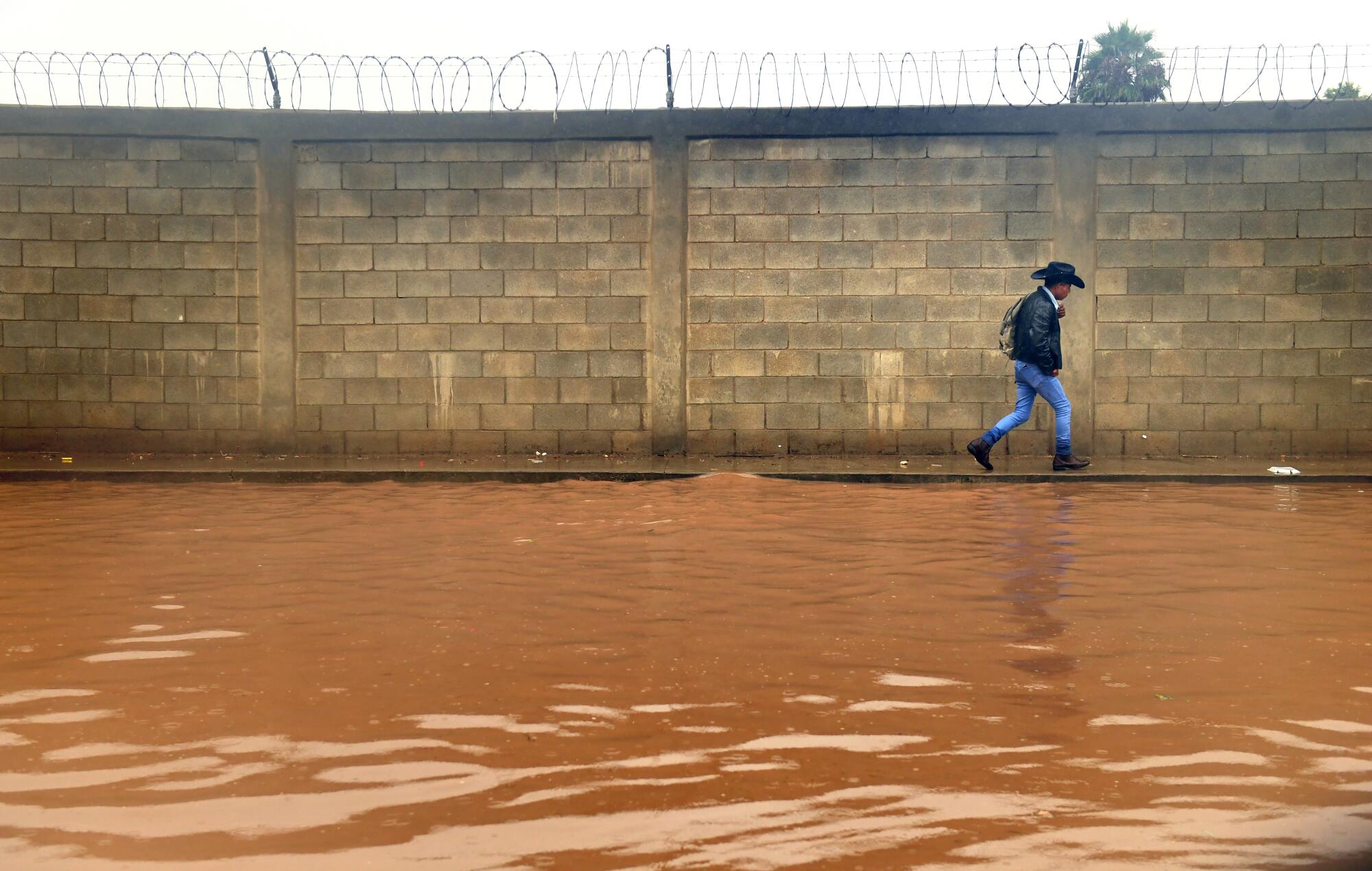 A pedestrian avoids a flooded street.