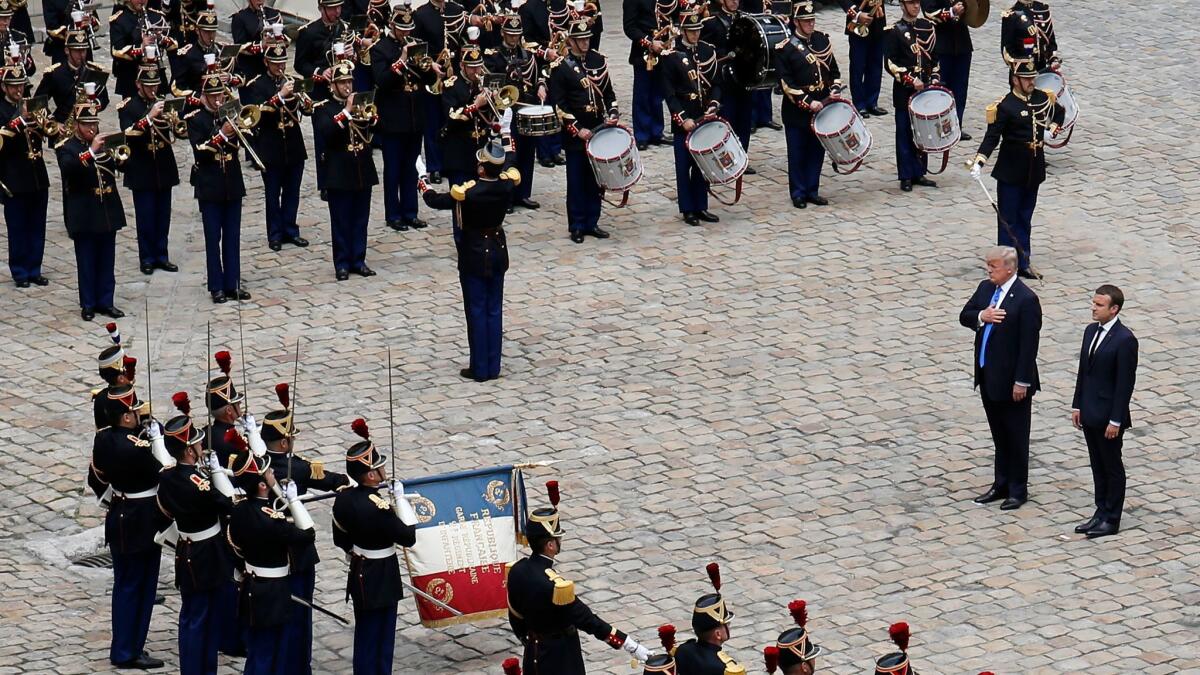 Presidents Trump and Emmanuel Macron listen to the French and U.S. national anthems during an official welcoming ceremony for Trump in the courtyard of Les Invalides in Paris.